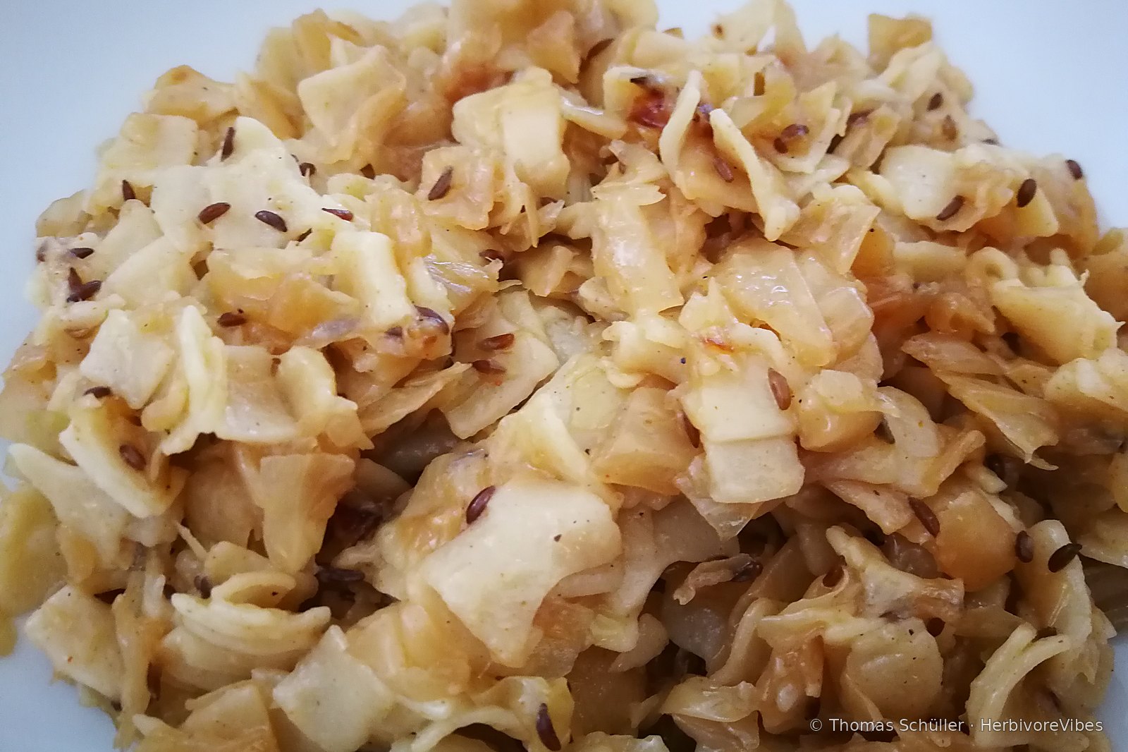 Krautfleckerl auf weißem Teller: goldbraun angebratenes Weißkraut mit Fleckerl-Nudeln und Kümmel